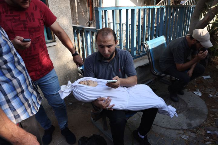 A photo by Agence France-Presse photographer Mohammed Abed shows a Palestinian man in Gaza City holding what appears to be a child wrapped in a shroud, Oct. 12, 2023. The website Alt News has cited the photo as evidence that contested footage posted last week by journalist Momen El Halabi is authentic.