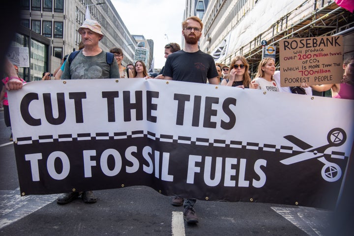 Protestors march with a large banner during the March To Demand An End To Fossil Fuels. 