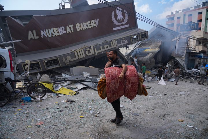 Παλαιστίνιοι περπατούν μπροστά από το αρτοποιείο Al Nuseirat, που καταστράφηκε σε ισραηλινή αεροπορική επιδρομή, στον προσφυγικό καταυλισμό Nusseirat στη Λωρίδα της Γάζας (18/10/2023)