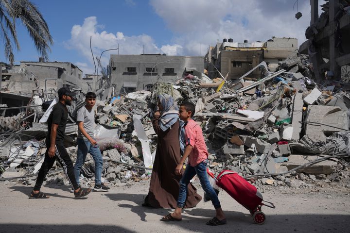 Παλαιστίνιοι περπατούν δίπλα σε κτίρια που καταστράφηκαν από ισραηλινές αεροπορικές επιδρομές στον προσφυγικό καταυλισμό Μπουρέιτζ, στη Λωρίδα της Γάζας (18/10/2023).
