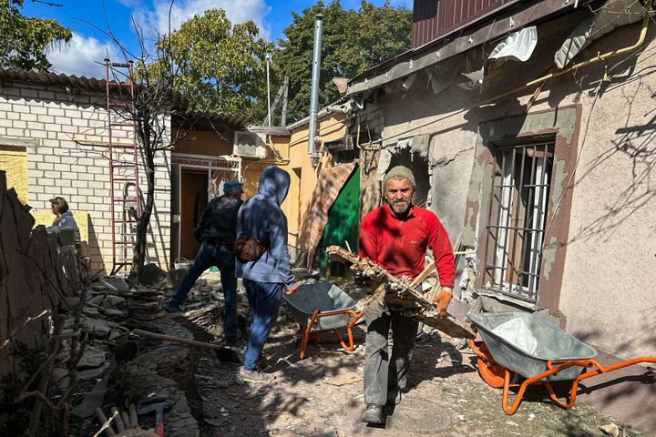 Local residents clean up the rubble in a damaged residential house after shelling on October 9, 2023 in Kherson, Ukraine.