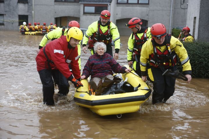 Members of the coastguard rescue a woman from flood waters surrounding her home in Brechin, Scotland.