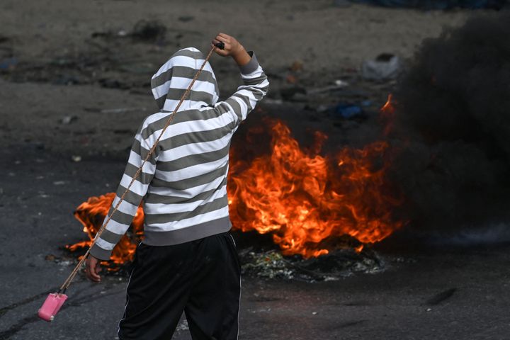 A Palestinian youth uses a slingshot to fire stones against Israeli security forces during clashes in the occupied West Bank city of Ramallah on October 20, 2023, amid ongoing battles between Israel and Hamas militants.