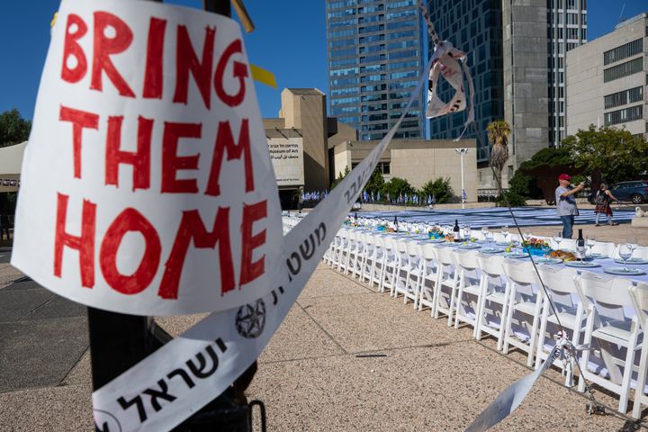 A "Bring Them Home" sign is displayed near a "Shabbat Dinner" table set for the families of hostages in the Tel Aviv museum plaza in Tel Aviv, Israel on Friday.