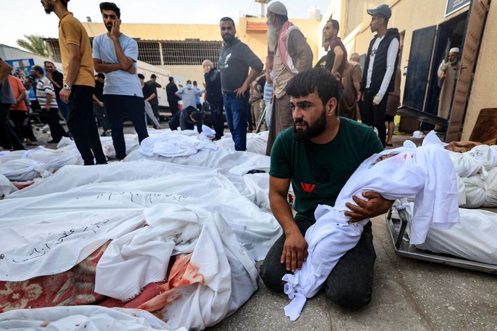 A man reacts as he carries the shrouded body of his child, in front of the morgue of the Al-Aqsa hospital in Deir Balah in the central Gaza Strip