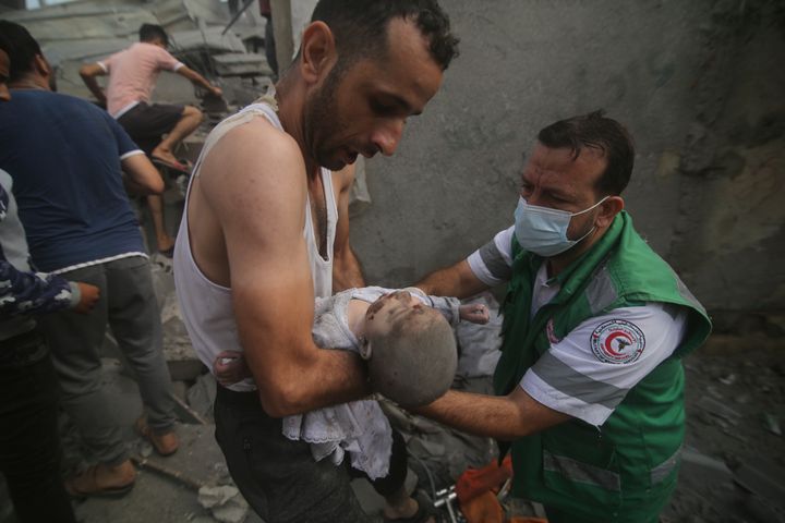 Petugas medis Palestina membawa bayi yang ditarik keluar dari gedung yang hancur akibat pemboman Israel di Jalur Gaza di Rafah, Minggu, 22 Oktober 2023. (AP Photo/Hatem Ali)