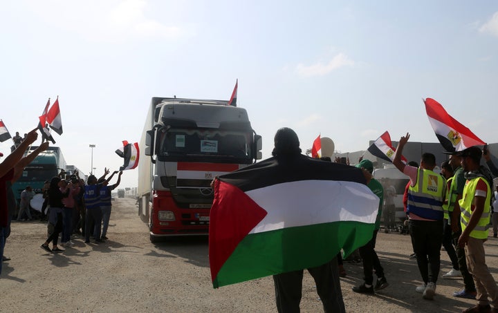 Volunteers wave Palestinian and Egyptian flags to a truck carrying humanitarian aid for the Gaza Strip as it crosses the Rafah border gate, in Rafah, Egypt, on Oct. 22, 2023.