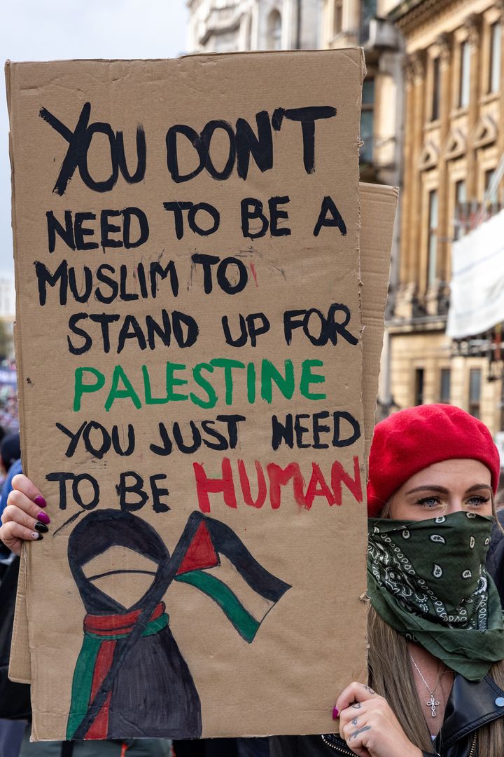 A pro-Palestinian protester holds a sign during a march through central London in support of the Palestinian population of Gaza on 21st October 2023.