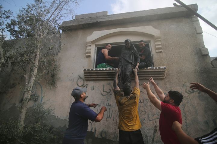 Νεαροί Παλαιστίνιοι στην Γάζα προσπαθούν να βοηθήσουν μια γυναίκα να εγκαταλείψει το σπίτι της που χτυπήθηκε κατά την διάρκεια ισραηλινών βομβαρδισμών. 