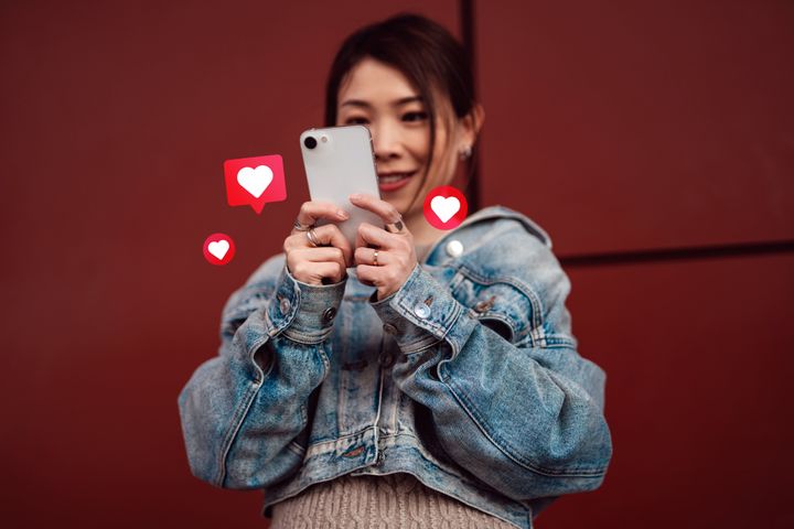 Low angle view of young Asian woman using smartphone on social media network application on the go, viewing or giving likes and commenting. Gen Z lifestyle and culture.