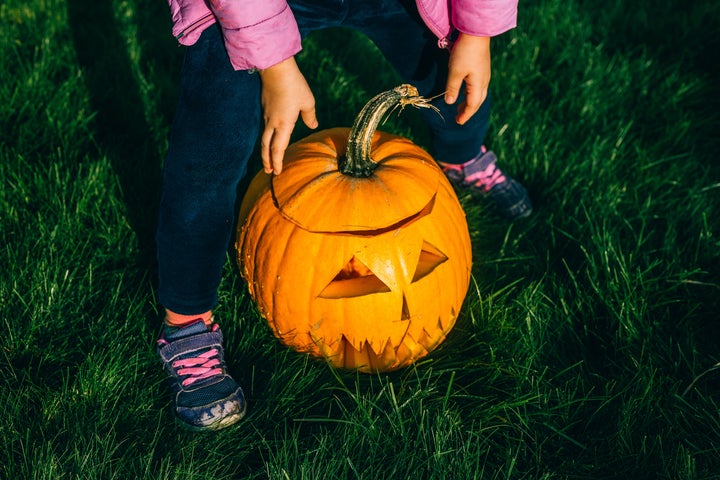 Kids making a Jack o Lantern on a grass