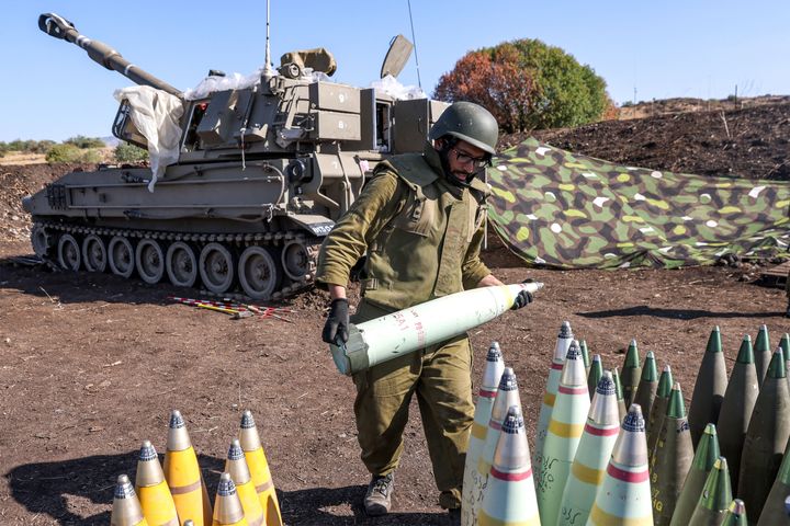 An Israeli soldier transports a 155mm artillery shell
