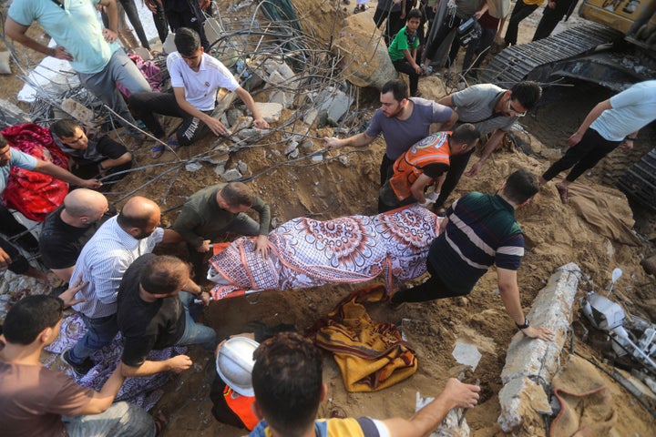 Palestinians carry a body of a dead person found under the rubble of a destroyed house after it was hit by an Israeli airstrike in the southern Gaza town of Khan Younis, Tuesday, Oct. 24, 2023.