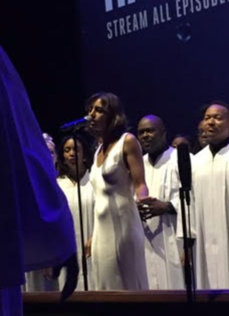 The author sings her song about The Man with a gospel choir at the "Hand of God" premiere in 2015.
