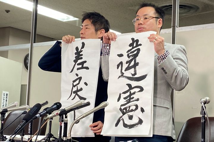 （左から）「違憲」「差戻し」と書かれた紙をもつ、南和行弁護士と吉田昌史弁護士（2023年10月25日）
