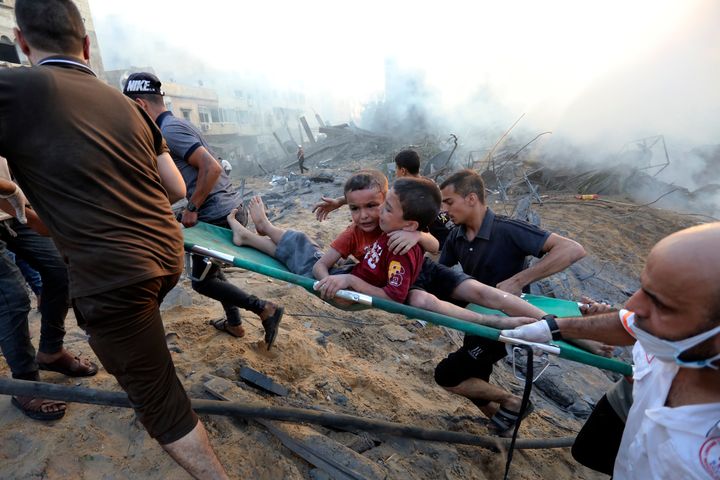 Palestinians evacuate two wounded boys out of the destruction following Israeli airstrikes on Gaza City, on Oct. 25, 2023. 