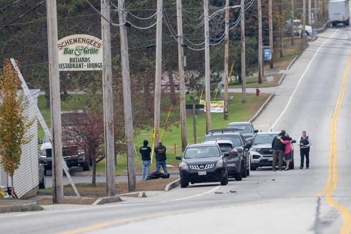 A woman hugs a law enforcement official outside the site of a mass shooting at Schemengees Bar and Grille in Lewiston, Maine.