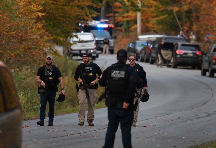 Law enforcement officials gather in the road leading to the home of suspect Robert Card.