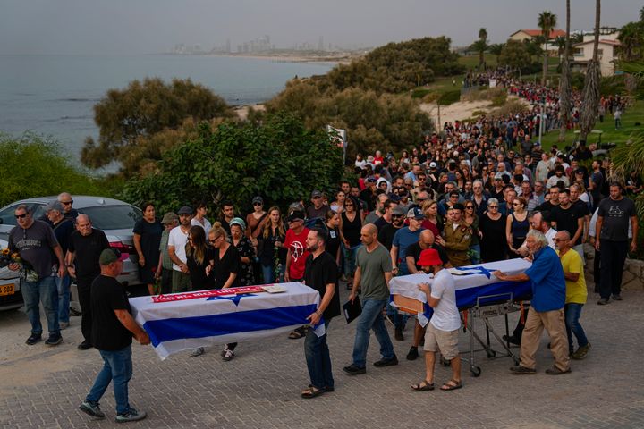 Mourners carry the coffins of Meni and Ayelet Godard, during their funeral in Kibbutz Palmachim, Israel Sunday, Oct. 29, 2023. The Israeli couple were killed by Hamas militants on Oct. 7, in Kibbutz Be'eri near the border with the Gaza Strip. More than 1,400 people were killed and some 220 captured in an unprecedented, multi-front attack on Israel by the militant group that rules Gaza. (AP Photo/Ariel Schalit)
