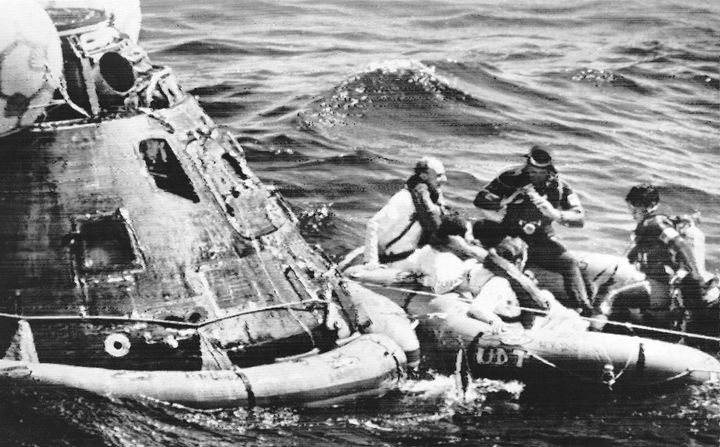 FILE - Apollo 16 astronauts, from left wearing white suits, Thomas Kenneth Mattingly, John Young and Charles Duke, pose for photographs by Navy Frogmen in rubber raft after leaving spaceship, left, in the Pacific Ocean on April 27, 1972. Mattingly, an astronaut who is best remembered for his efforts on the ground that helped bring the damaged Apollo 13 spacecraft safely back to Earth, has died Tuesday, Oct. 31, 2023, NASA announced. (AP Photo, File)