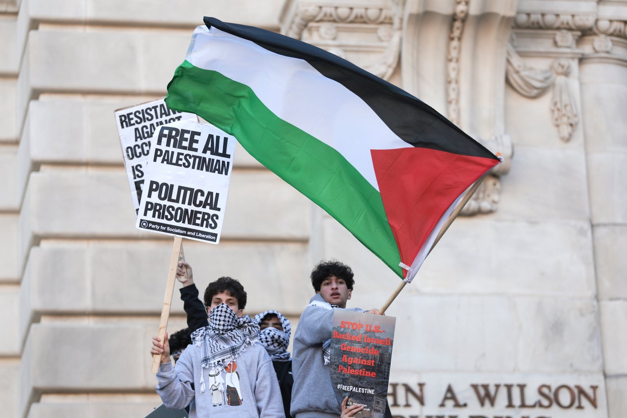 Protesters wave signs and flags outside a government building near the White House.