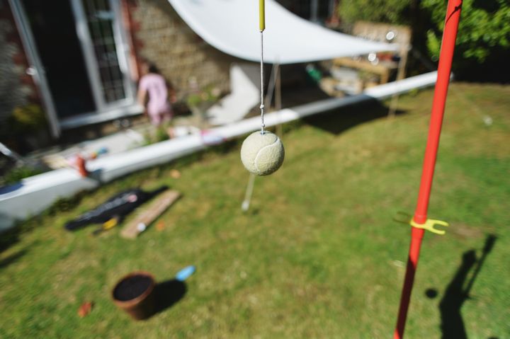 Sunny backyard garden with tennis ball swingball game with house in the background