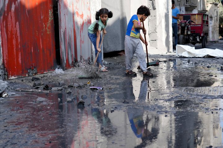 Palestinian children mop outside their home after an Israeli bombardment in the Maghazi refugee camp in the Gaza Strip on Nov. 5, 2023. 