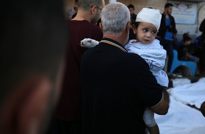 A Palestinian man carries an injured child following the Israeli bombardment of Deir Balah in the central Gaza Strip, outside the Shuhada Al-Aqsa hospital in the same city on November 6, 2023.