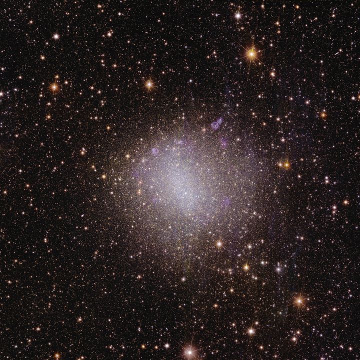 Esta imagem da galáxia irregular conhecida como “NGC 6822” mostra características de uma galáxia em seu desenvolvimento inicial.  Ao contrário da Via Láctea, que tem um formato distinto, a NGC 6822 é irregular e pequena.