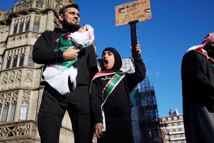 A young girl chants slogans while her father carries a mock dead child during a march for ceasefire in Gaza on Saturday. 