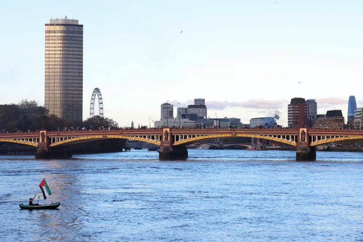 Pro-Palestinian demonstrators march over the Vauxhall Bridge in London as a boater raises a Palestinian flag in solidarity.