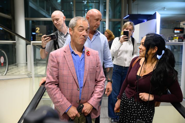 Farage speaking to members of the press as he makes his way through Arrivals
