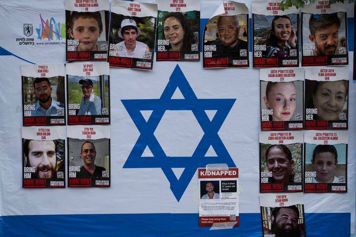Photographs of Israelis who were kidnapped during Hamas' unprecedented attack on Israel on Oct. 7 are glued atop a poster of the Israeli flag on a board in Jerusalem on Monday, Nov. 13, 2023. (AP Photo/Bernat Armangue)