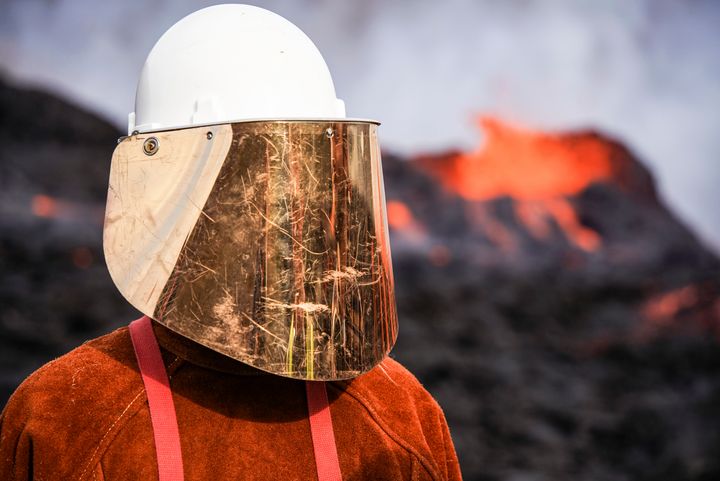 A person wears protective gear as they stand close to the lava flowing from Fagradalsfjall volcano in Iceland on Wednesday, Aug. 3, 2022.