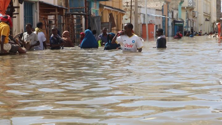 Άνθρωποι περπατούν μέσα από έναν πλημμυρισμένο δρόμο σε μια κατοικημένη περιοχή στην πόλη Μπελεντουέινε στη Σομαλία (15/112023)