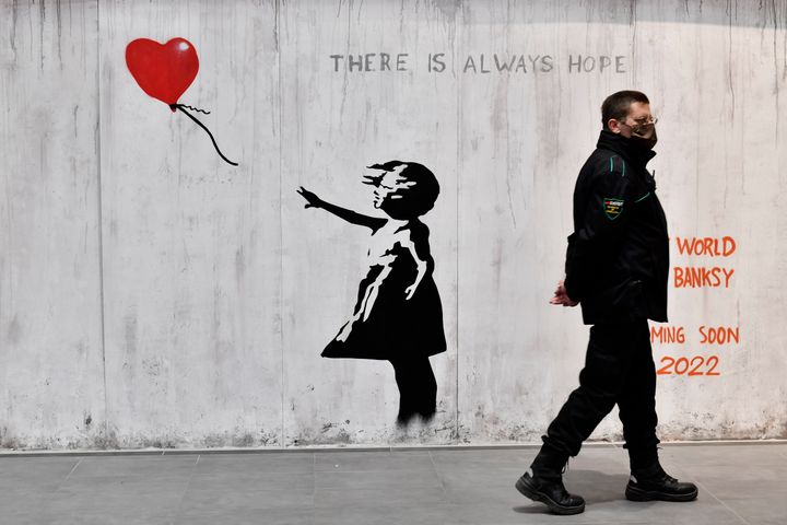 A man walks near a Banksy artwork during the "World of Banksy" art exhibition in 2022 in Turin, Italy.