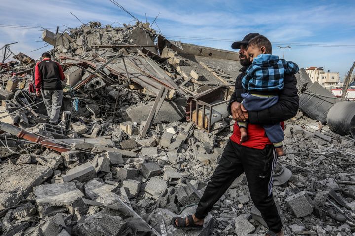 Palestinians walk around the rubble, after an Israeli air strike on a house.