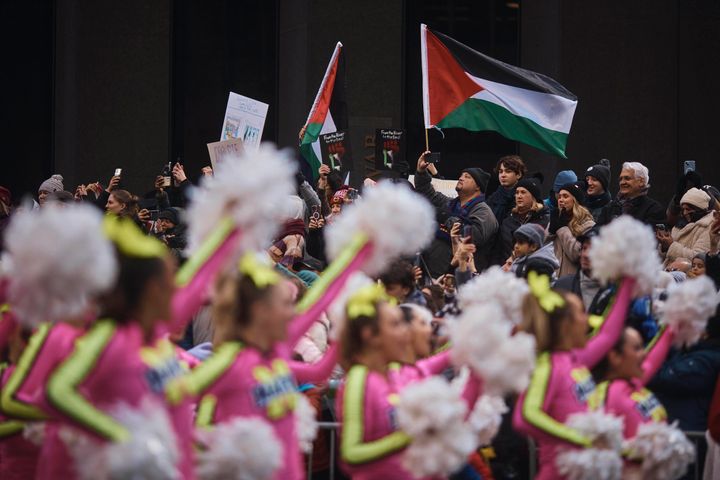 Protesters wave Palestinian flags as performers move along 6th Avenue.