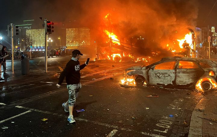Flames rise from a car and a bus, set alight at the junction of Bachelors Walk and the O'Connell Bridge, in Dublin on Nov. 23, 2023, as people took to the streets in protest following the stabbings earlier in the day.