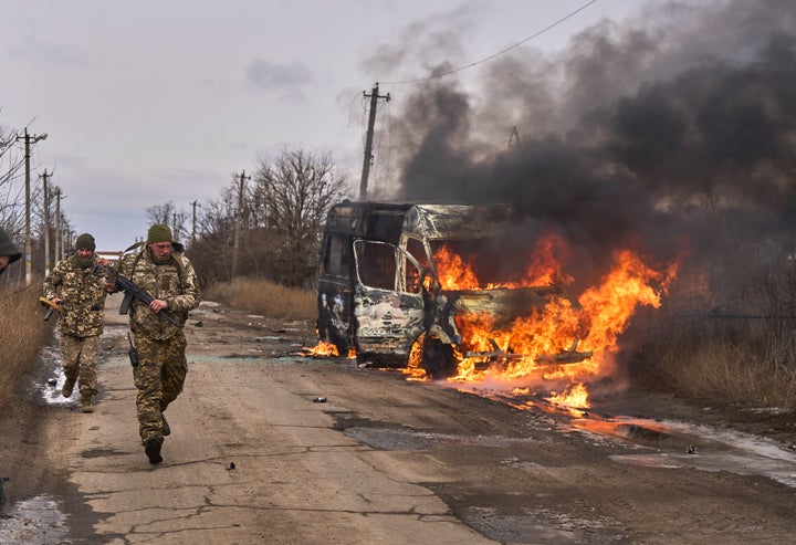 In this photo provided by the Ukrainian 10th Mountain Assault Brigade "Edelweiss", Ukrainian soldiers pass by a volunteer bus burning after a Russian drone hit it near Bakhmut, Donetsk region, Ukraine.