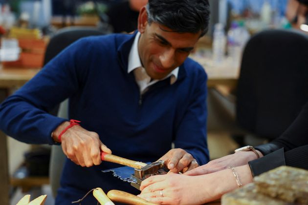 Rishi Sunak holding a hammer the wrong way.