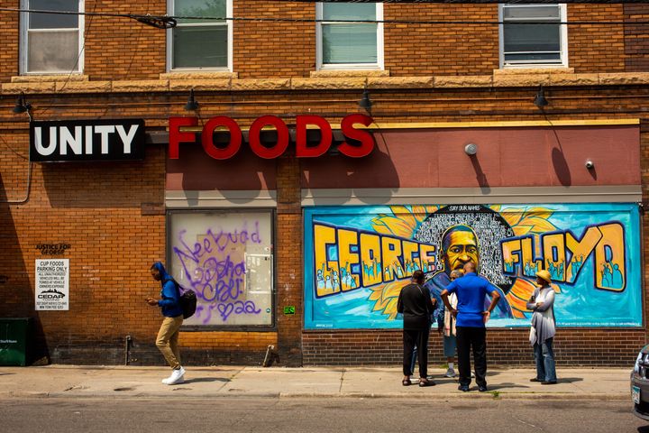 Visitors talk near the mural outside of Unity Foods, formerly Cup Foods, at George Floyd Square Friday, June 16, 2023 in Minneapolis, Minnesota. (Photo by Nicole Neri for the Washington Post)