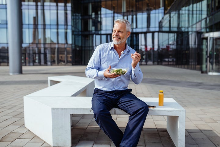 Senior businessman dressed in blue shirt in front of office building