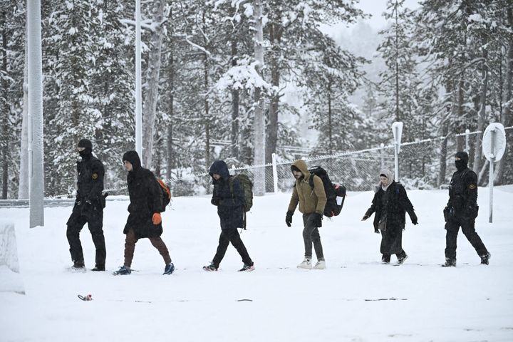 Finnish border guard officers escort migrants upon arrival at the Raja-Jooseppi border crossing station to Russia in Inari, northern Finland, on Nov. 25, 2023.