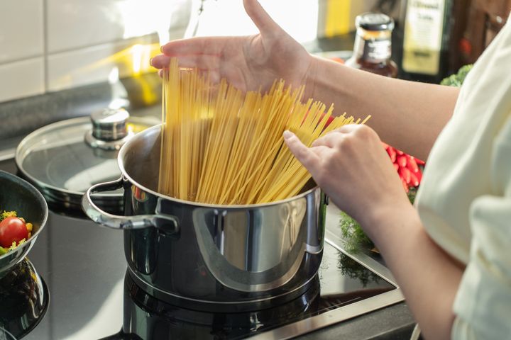 Girl cooking pasta in the kitchen, bowling pasta in pot.