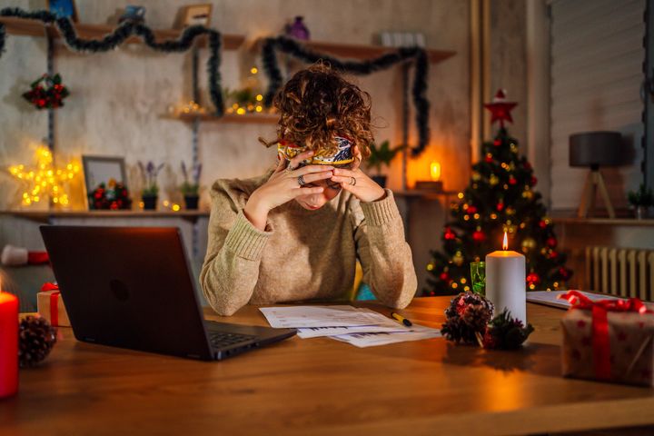 Exhausted young woman working at home late at night during Christmas holidays