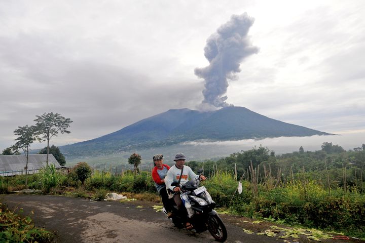 Motorists ride past by as Mount Marapi spews volcanic materials during its eruption in Agam, West Sumatra, Indonesia, on Dec. 4, 2023. 