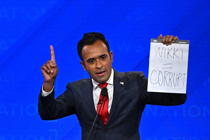 Entrepreneur Vivek Ramaswamy holds up a sign reading "Nikki = corrupt" referring to one of his rivals, former South Carolina Gov. Nikki Haley, at the GOP presidential debate Wednesday in Tuscaloosa, Alabama.