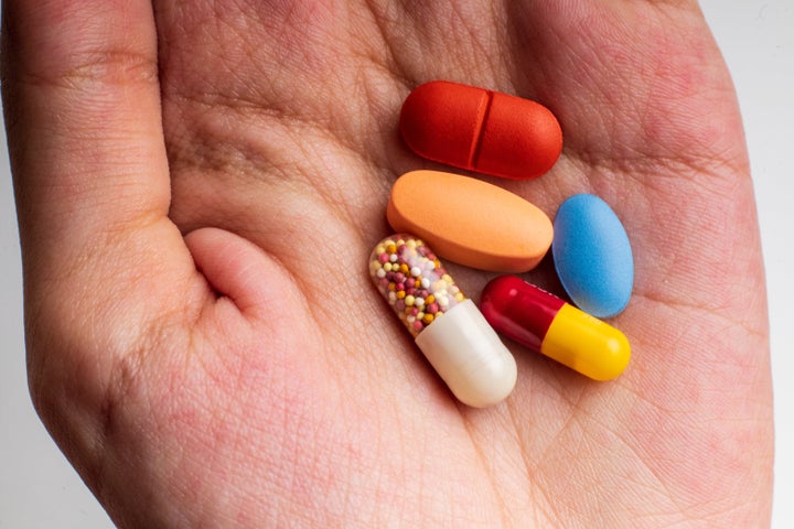 Young woman holding pills, close-up of hand