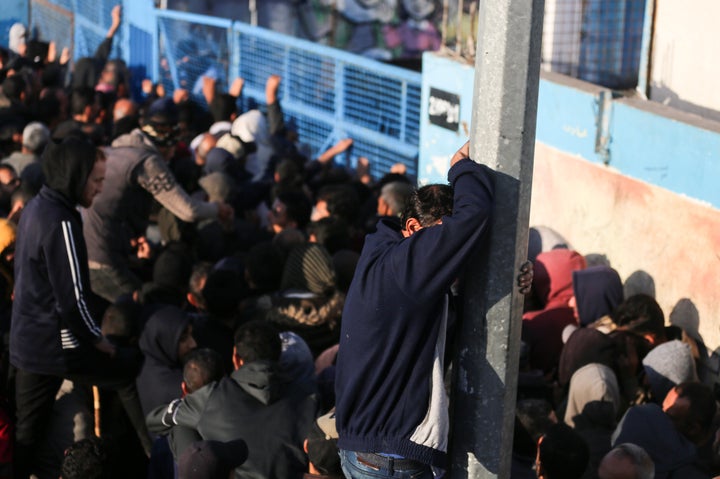 Palestinians wait to receive food supplies at an aid distribution center run by the United Nations Relief And Works Agency (UNRWA), in Central Gaza's Deir El-Balah, On December 7, 2023.